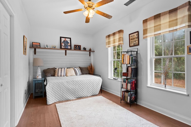 bedroom featuring ceiling fan, light hardwood / wood-style floors, and multiple windows