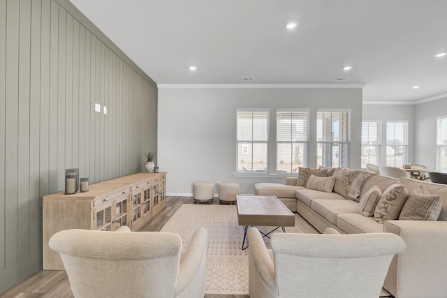 living room with crown molding, a healthy amount of sunlight, and light wood-type flooring