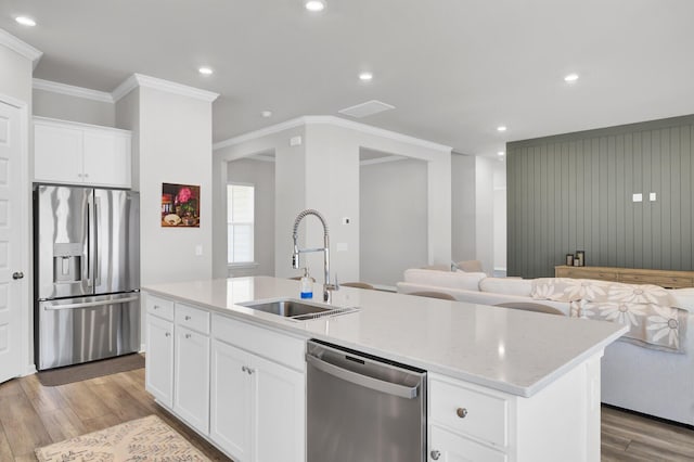 kitchen with sink, appliances with stainless steel finishes, a kitchen island with sink, white cabinetry, and light wood-type flooring