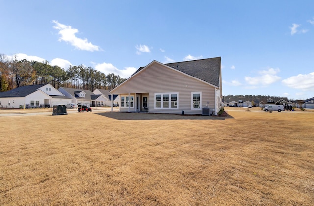 rear view of property with central AC unit and a lawn