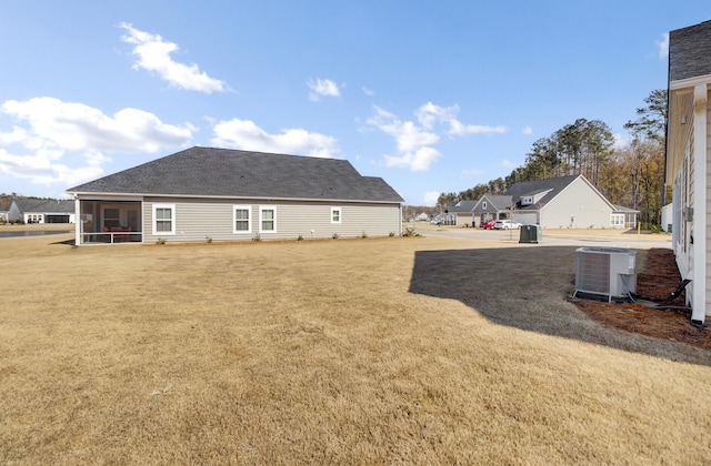 rear view of property featuring a yard, central AC unit, and a sunroom