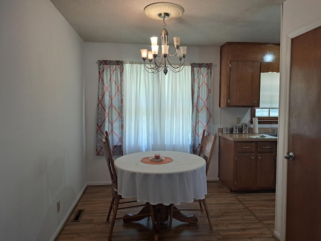 dining area featuring wood finished floors, a chandelier, visible vents, and a textured ceiling