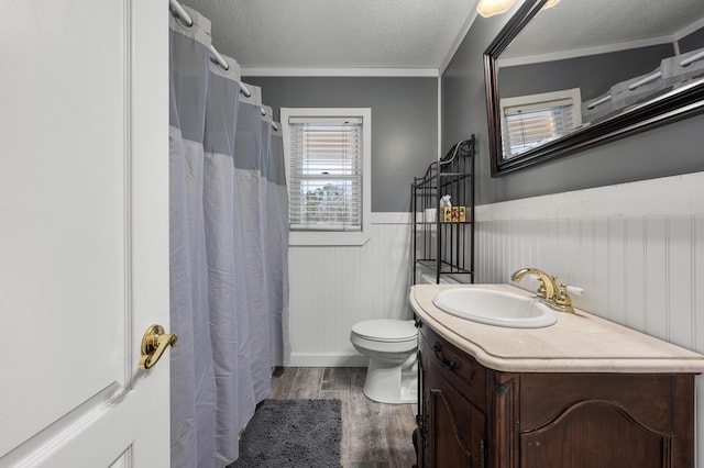 bathroom with vanity, toilet, ornamental molding, a textured ceiling, and wood-type flooring