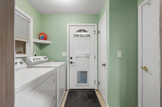 laundry area with light tile patterned flooring, a textured ceiling, and washing machine and clothes dryer