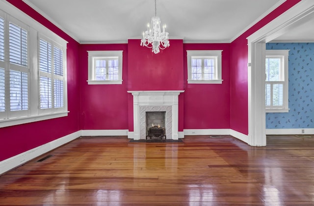 unfurnished living room with a notable chandelier, a high end fireplace, hardwood / wood-style floors, and crown molding