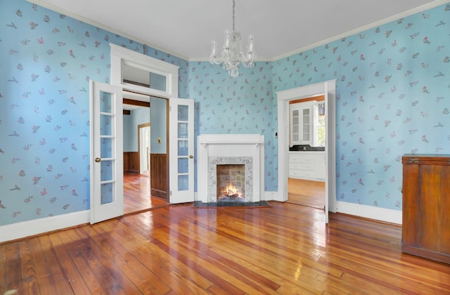 unfurnished living room featuring wood-type flooring, a notable chandelier, and crown molding