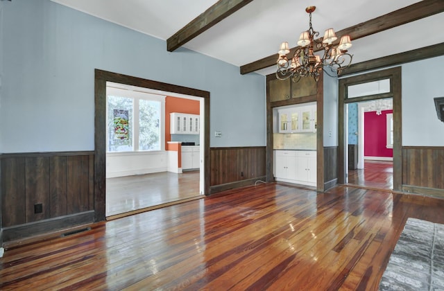 interior space with dark wood-type flooring, beam ceiling, and a notable chandelier