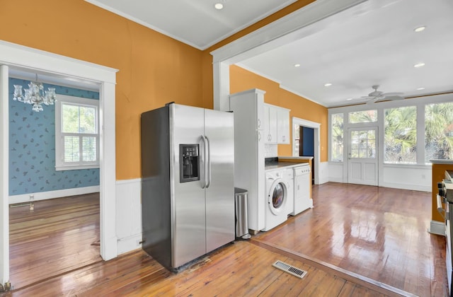 kitchen with hardwood / wood-style floors, washing machine and clothes dryer, white cabinetry, stainless steel refrigerator with ice dispenser, and ornamental molding