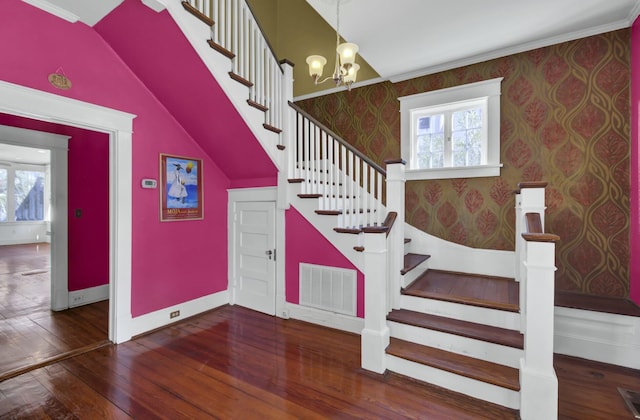 stairway featuring wood-type flooring, crown molding, and an inviting chandelier