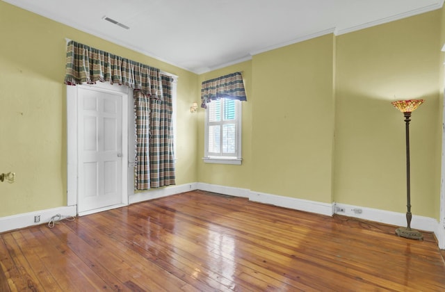 empty room with hardwood / wood-style floors and crown molding