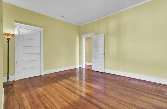 empty room featuring crown molding and wood-type flooring