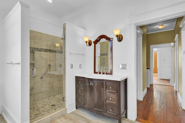 bathroom with wood-type flooring, walk in shower, crown molding, and vanity