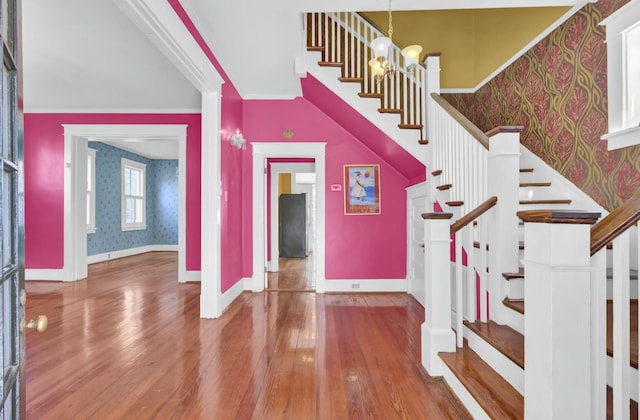 stairs with hardwood / wood-style floors, an inviting chandelier, and ornamental molding