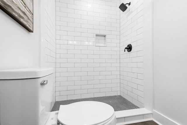 bathroom with a tile shower and toilet