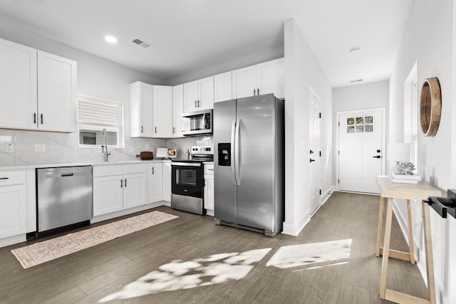 kitchen featuring decorative backsplash, appliances with stainless steel finishes, dark hardwood / wood-style flooring, sink, and white cabinets