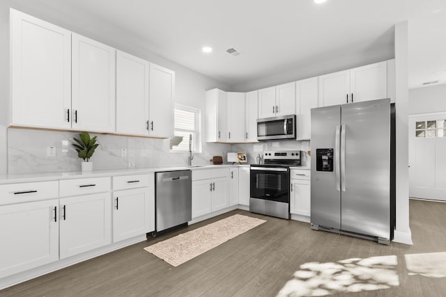 kitchen featuring backsplash, white cabinets, and stainless steel appliances