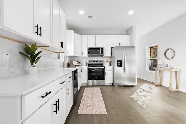 kitchen featuring dark wood-type flooring, white cabinets, sink, appliances with stainless steel finishes, and tasteful backsplash