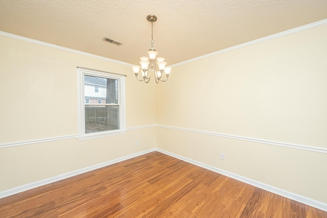 spare room featuring crown molding, a notable chandelier, hardwood / wood-style flooring, and a textured ceiling