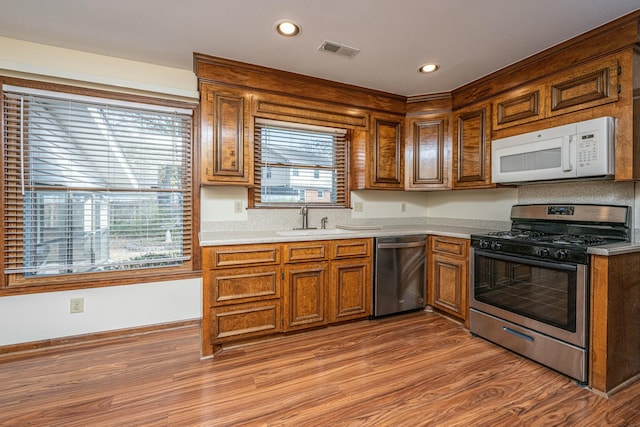 kitchen featuring appliances with stainless steel finishes, sink, and light hardwood / wood-style floors