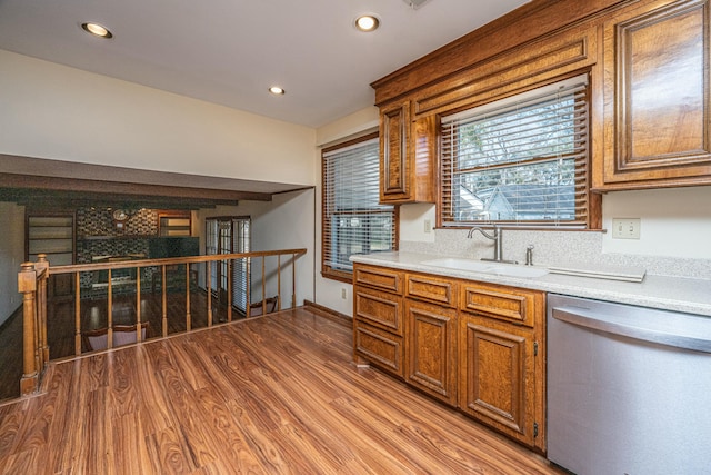 kitchen featuring dishwasher, sink, backsplash, and light hardwood / wood-style flooring