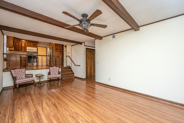 unfurnished room with ceiling fan, beam ceiling, light hardwood / wood-style flooring, and a textured ceiling