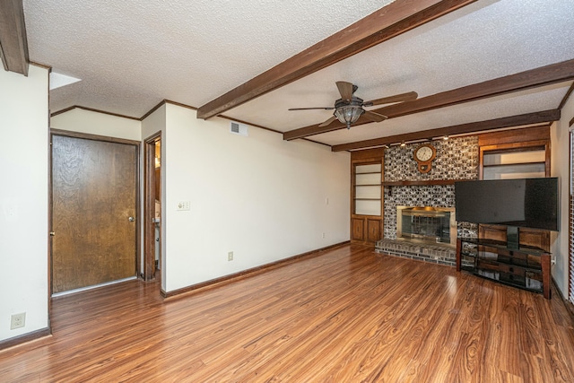 unfurnished living room with hardwood / wood-style floors, beamed ceiling, a fireplace, and a textured ceiling