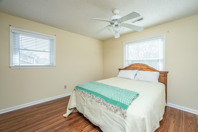 bedroom featuring ceiling fan, dark wood-type flooring, and a textured ceiling