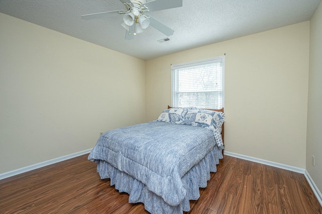 bedroom with ceiling fan, dark hardwood / wood-style floors, and a textured ceiling