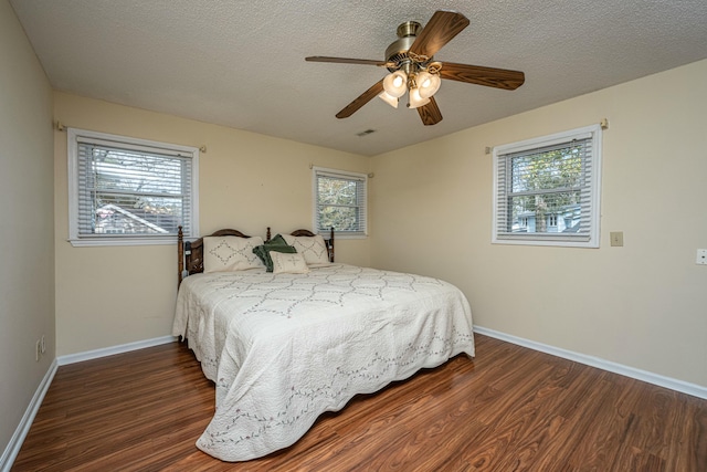 bedroom with dark hardwood / wood-style flooring, multiple windows, and a textured ceiling