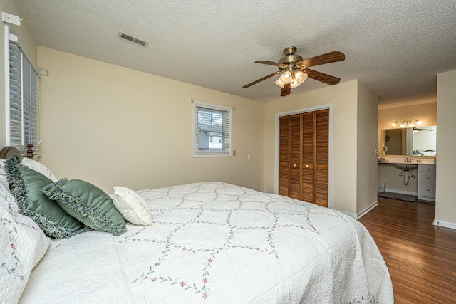 bedroom with connected bathroom, a textured ceiling, dark hardwood / wood-style flooring, a closet, and ceiling fan