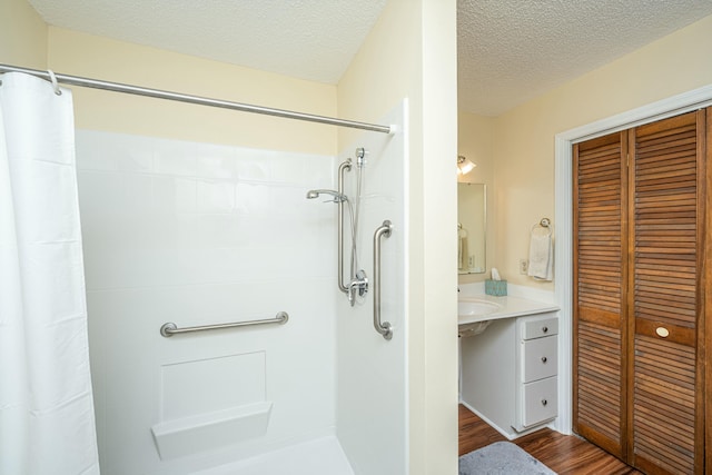 bathroom with vanity, hardwood / wood-style floors, a shower with curtain, and a textured ceiling