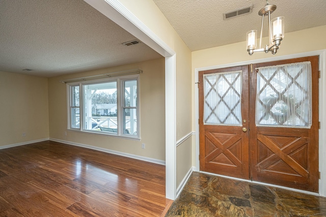 entryway with dark hardwood / wood-style flooring, a textured ceiling, and an inviting chandelier