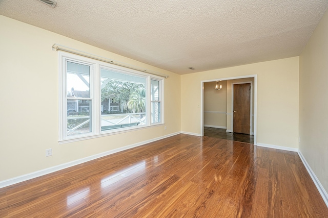 unfurnished room with hardwood / wood-style flooring and a textured ceiling