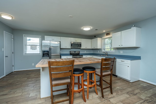 565 Estates Dr, Walterboro, SC 29488 - kitchen with stainless steel appliances, white cabinets, wood finished floors, a kitchen island, and a kitchen bar