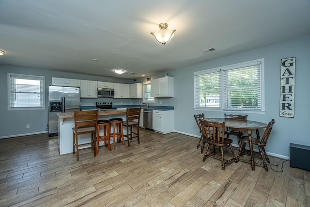 565 Estates Dr, Walterboro, SC 29488 - kitchen featuring appliances with stainless steel finishes, light wood-type flooring, a kitchen island, white cabinets, and a breakfast bar
