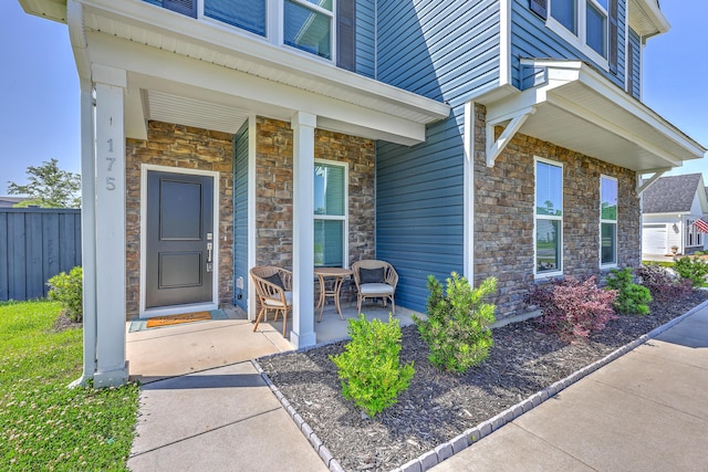 175 Darby Meadow Ln, Ridgeville, SC 29472 - doorway to property with stone siding, covered porch, and fence