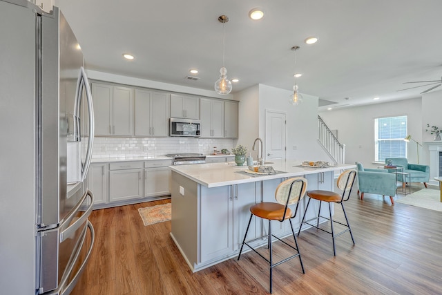175 Darby Meadow Ln, Ridgeville, SC 29472 - kitchen with appliances with stainless steel finishes, open floor plan, light wood-type flooring, backsplash, and a breakfast bar area