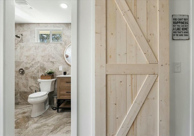 bathroom with vanity, tile walls, and toilet