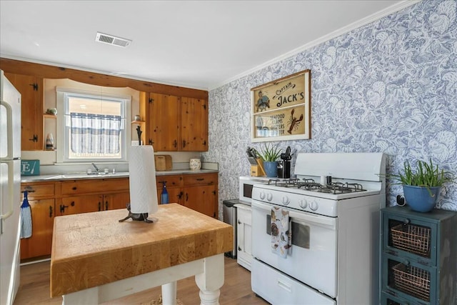 kitchen with sink, white appliances, light hardwood / wood-style flooring, and ornamental molding