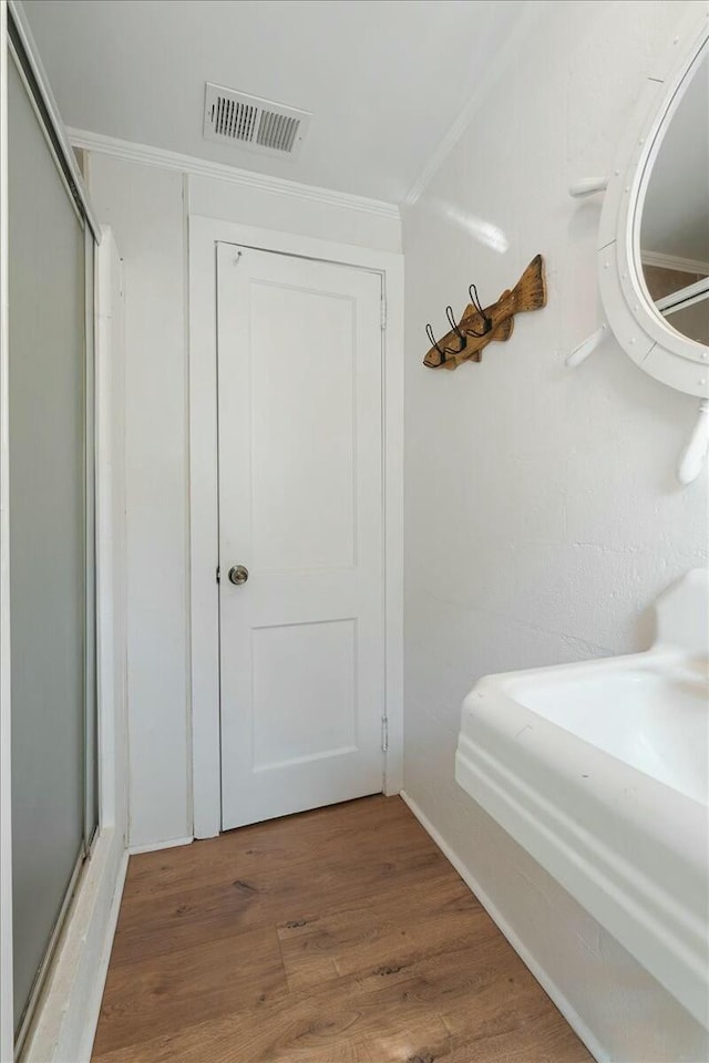 bathroom with ornamental molding and wood-type flooring