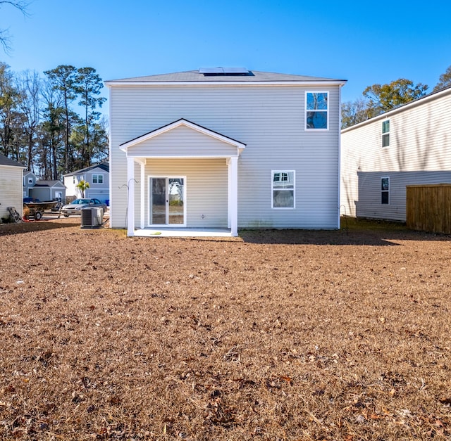 rear view of house with central air condition unit, a patio, and solar panels