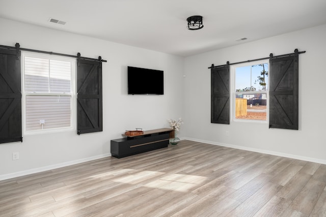 interior space with a barn door, light hardwood / wood-style floors, and a wealth of natural light