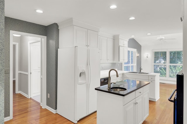 kitchen with a kitchen island with sink, light wood-style flooring, a sink, and white fridge with ice dispenser