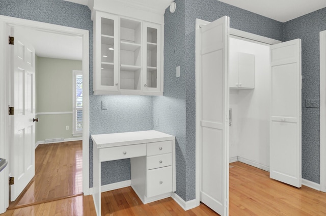unfurnished office with baseboards, light wood-style flooring, visible vents, and wallpapered walls