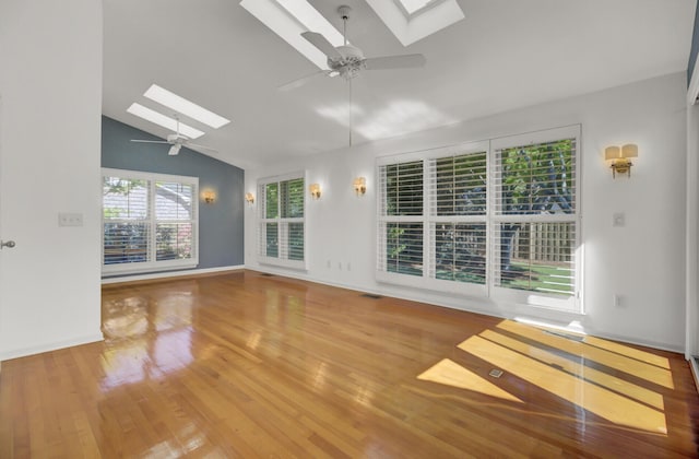 interior space with baseboards, vaulted ceiling with skylight, visible vents, ceiling fan, and wood finished floors