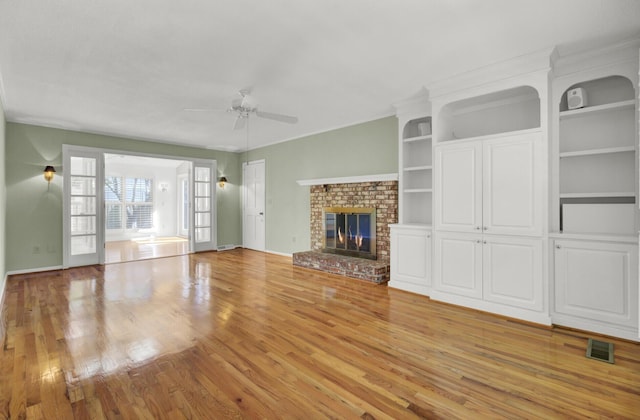 unfurnished living room with a fireplace, light wood-style flooring, a ceiling fan, visible vents, and baseboards