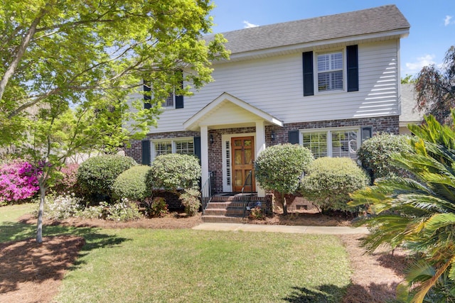 view of front facade featuring brick siding, a front lawn, and a shingled roof