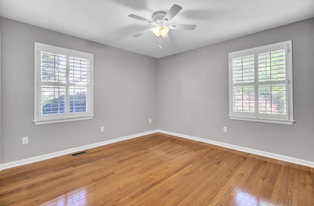 spare room featuring visible vents, baseboards, light wood-type flooring, and a ceiling fan