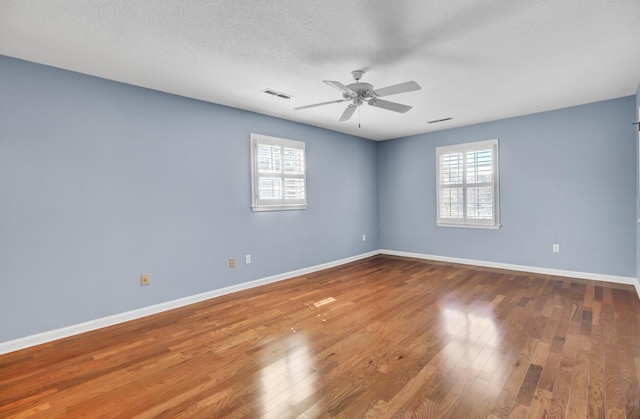 unfurnished room featuring visible vents, ceiling fan, hardwood / wood-style flooring, and baseboards