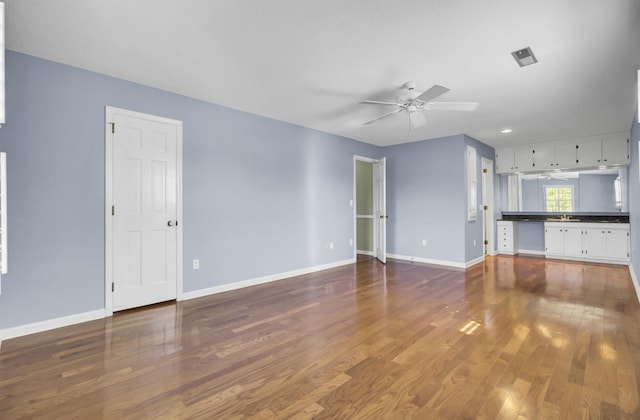 unfurnished living room with wood finished floors, ceiling fan, and baseboards